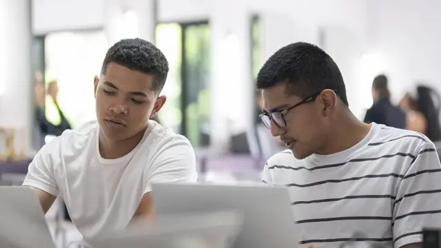 Dos jóvenes frentes a sus computadoras