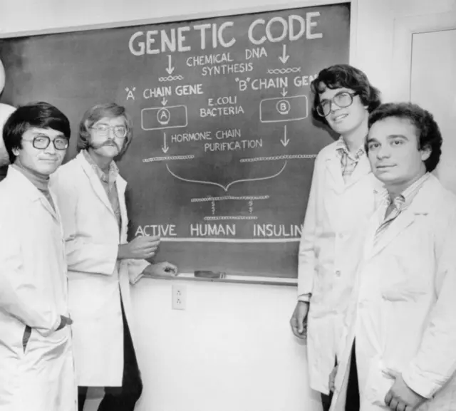 Los científicos de City of Hope Keiichi Itakura, Arthur D. Riggs, David V. Goeddel de Genetech y Roberto Crea frente a un tablero explican cómo su esfuerzo conjunto en ingeniería genética dio como resultado la primera insulina humana producida artificialmente.