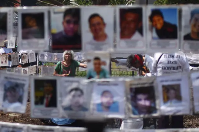 Unos familiares de desaparecidos junto a fotos de ellos en México