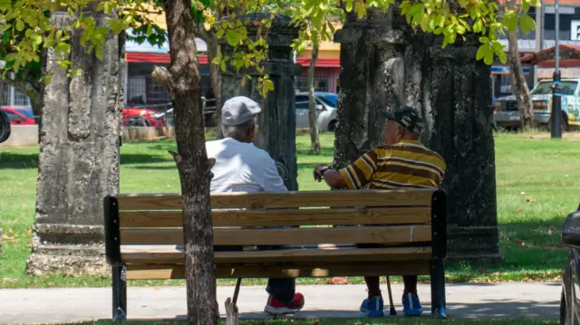 dos hombres sentados en una plaza de barrio obrero, en San Juan, Puerto Rico