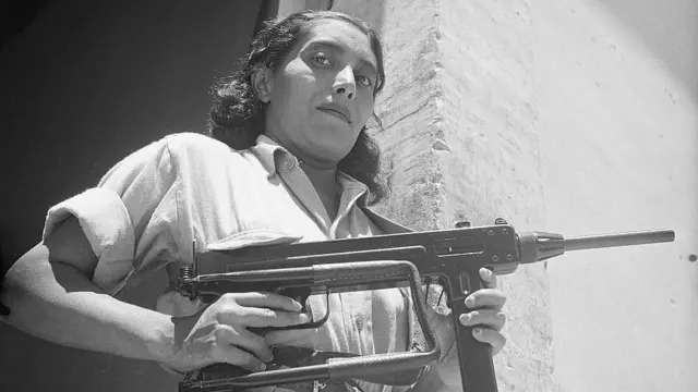 Una mujer sostiene un arma. 