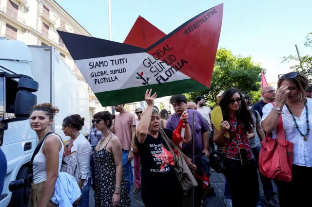 Una mujer con una pancarta en forma de barquito en apoyo a la flotilla humanitaria que se dirige a Gaza en Nápoles, Italia, el 22 de septiembre de 2025.