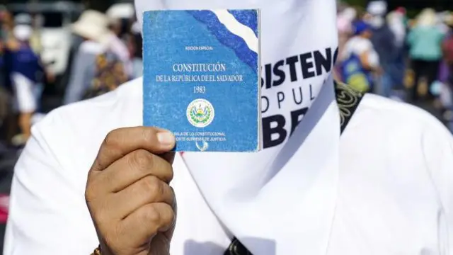 Un hombre sostiene una copia de la Constitución de El Salvador