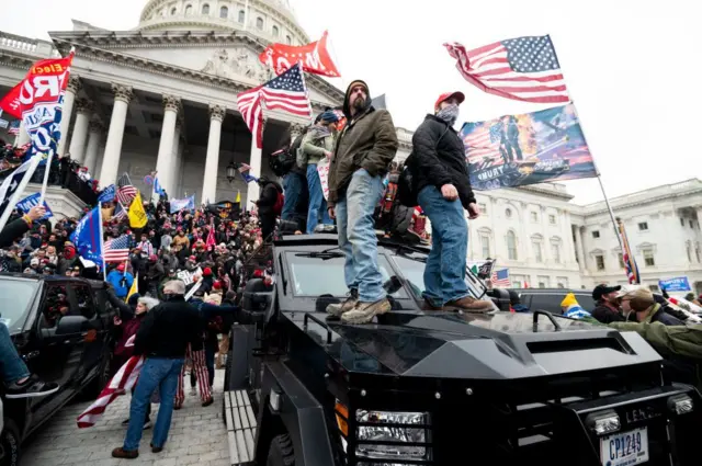 Personas con banderas de EE.UU. frente al Capitolio.