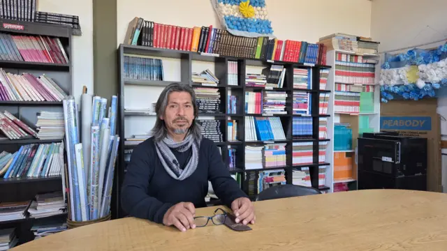 Maestro sentado en una biblioteca.