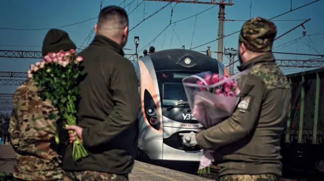 Soldados con ramos de flores en una estación de tren en Ucrania. 