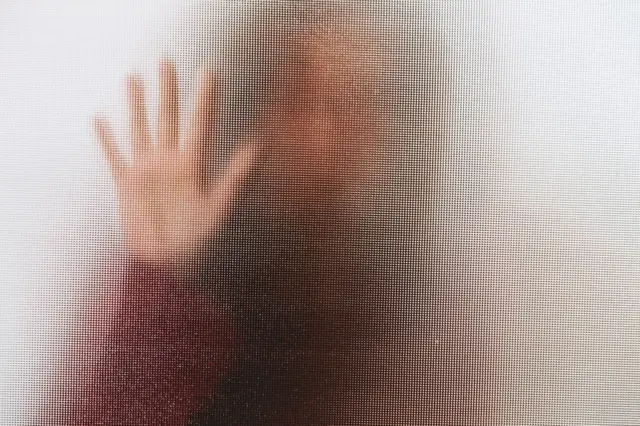 Una mujer detrás de un vidrio que no permite identificarla