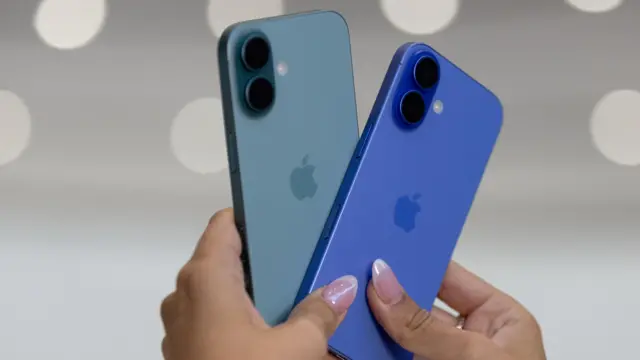 Las manos de una mujer sostiene dos teléfonos iPhone 16 azules en un evento de lanzamiento en septiembre.