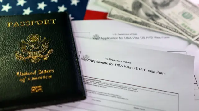 Una composicón de un pasaporte con las palabras borrosas sobre una solicitud para la visa H-1B con la bandera de EE.UU. de fondo y dólares.