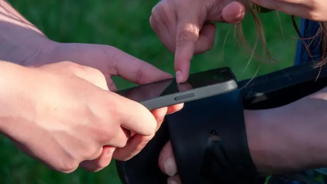 Dos niños miran la pantalla de un celular.