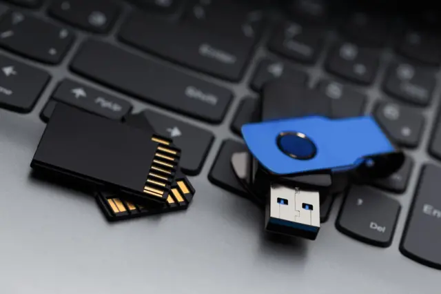 Una par de tarjetas SD y un pendrive azul en el teclado de un laptop.