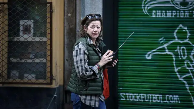 Una mujer en la calle sintoniza una radio.