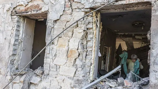 Una mujer mayor camina en su casa, gravemente dañada por un ataque ruso en la ciudad de Druzhkivka, Ucrania. 