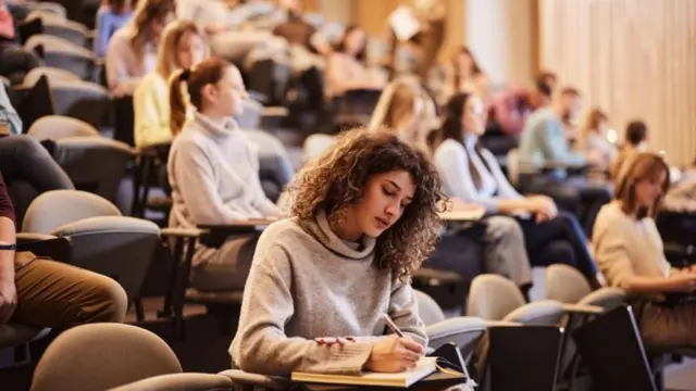 Joven tomando notas en una clase en la universidad. 