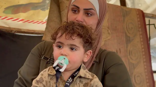 Nihaya con los ojos llenos de lágrimas tiene en su falda a su hijo Mohammed, de poco más de 1 año