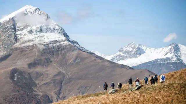 Una decena de montañistas observan desde la distancia el pico nevado de Monviso 