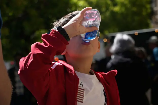 Un niño bebe agua de una botella plástica.