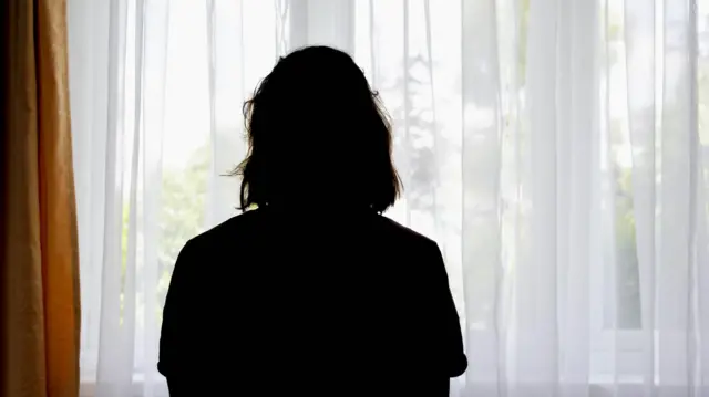 Una mujer mira hacia afuera por la ventana. 