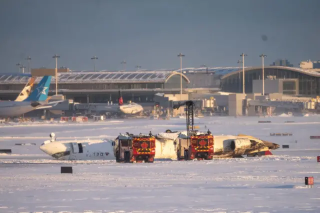 Los restos de un avión pequeño, volteado, en la pista de aterrizaje del aeropuerto internacional de Toronto, Canadá.