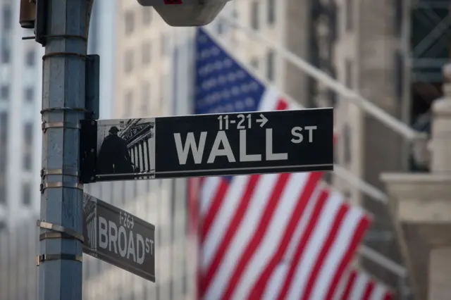 Señal en la calle que dice Wall Street con el fondo de la bandera de EE.UU.