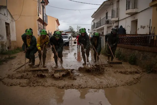 Personas limpiando el barro. 