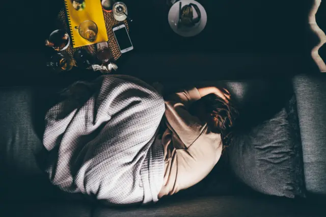 Mujer durmiendo acurrucada en un sofá