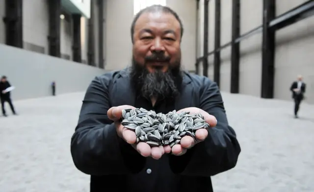 Ai Weiwei muestra semillas de girasol de porcelana a la cámara.