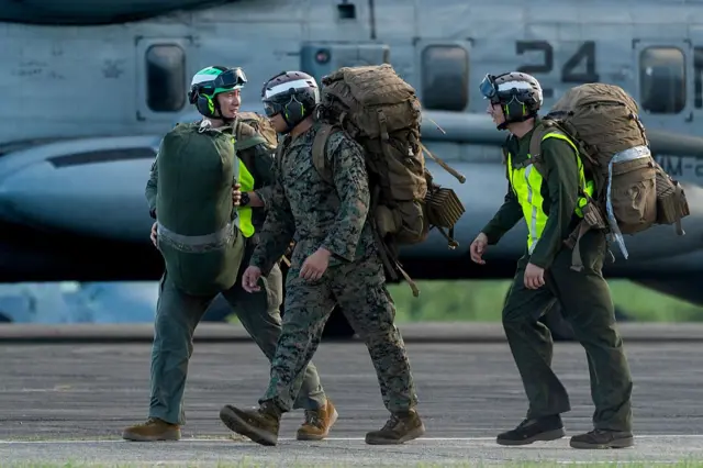 Tres soldados estadounidenses caminan cargados con sus bolsos en la antigua base naval de Roosevelt Roads.
