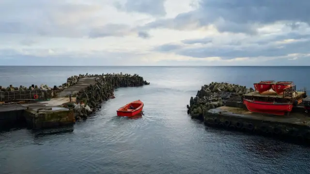 Barca vacía, puerto, mar y horizonte