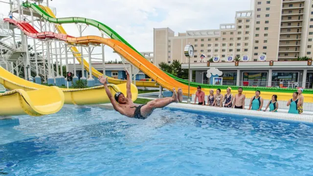 Turistas nacionales observan cómo un hombre usa un tobogán para nadar en una piscina en el parque acuático Myongsasimni en la zona turística costera Wonsan Kalma en Wonsan, provincia de Kangwon, Corea del Norte.