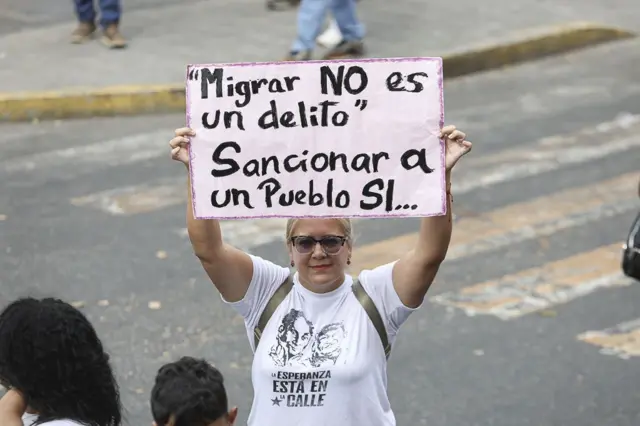 Una mujer sostiene un cartel que dice que migrar no es un delito.