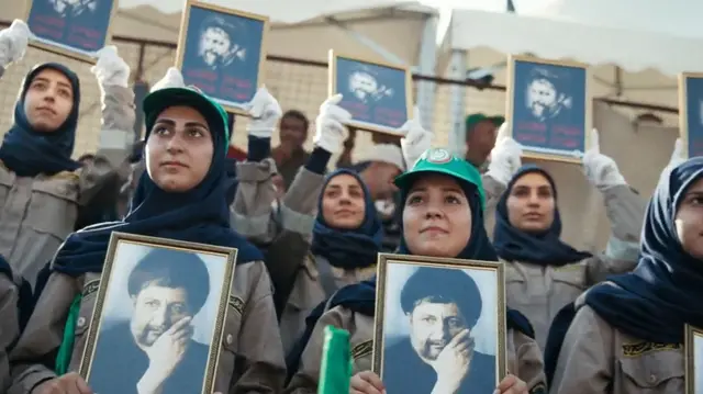 Mujeres con gorras verdes, bufandas negras y uniformes caqui, sostienen fotos de Musa al-Sadr durante una manifestación en el aniversario de su desaparición    