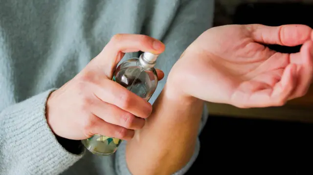 Persona poniéndose perfume