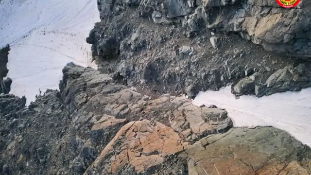 Un barranco rocoso y empinado con nieve en el centro