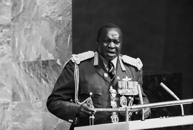 Imagen en blanco y negro del presidente de Uganda Idi Amin, quien viste un uniforme militar de mariscal de campo con muchas condecoraciones mientras habla desde el podio de la Asamblea General de la ONU.