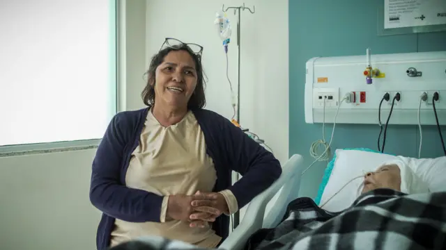 Una mujer junto a su esposo quiene está en una cama de hospital