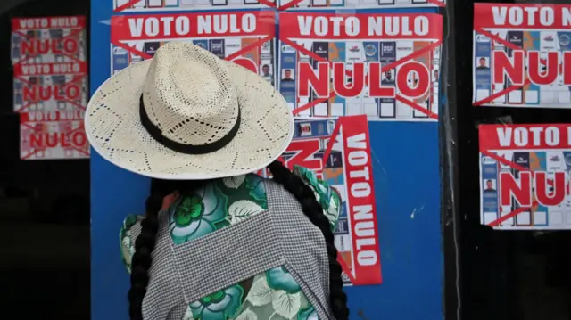 Una mujer pega un cartel que dice 