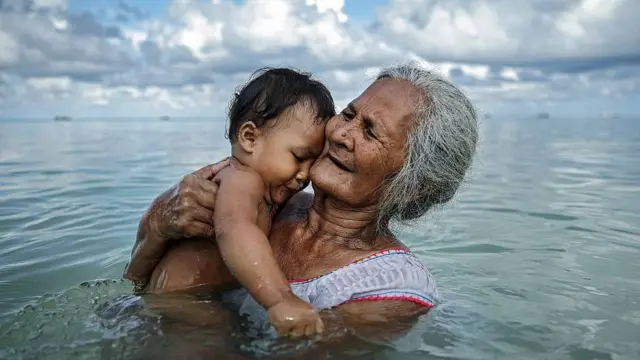 Una abuela en Tuvalu baña a su nieto en una laguna interna