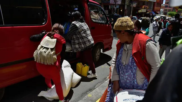 Mujeres bolivianas cargan víveres en una furgoneta en un mercado local en La Paz el 18 de diciembre de 2025. 