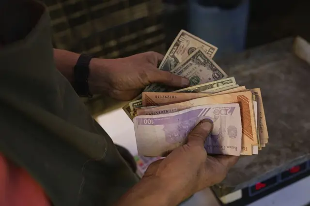 Un vendedor contando dólares y bolívares