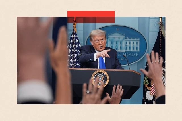 Trump señala a una audiencia, de pie detrás de un atril, mientras la gente levanta la mano para hacer preguntas.