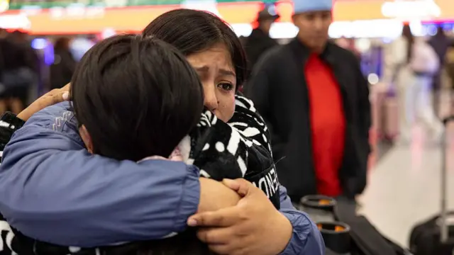 La inmigrante ecuatoriana Andrea, de 28 años, recibe un largo abrazo de su hermana (de frente a la cámara) antes de su vuelo a Ecuador en el Aeropuerto Internacional JFK el 26 de octubre de 2025 en Nueva York, Nueva York. Andrea y su prima decidieron “auto-deportarse” con sus hijos después de que sus esposos fueran detenidos por agentes del Servicio de Inmigración y Control de Aduanas de Estados Unidos (ICE) y luego deportados a Ecuador debido a su estatus indocumentado. La hija menor de Andrea, Shanell, de 7 meses, nació en Estados Unidos y es ciudadana estadounidense. (Foto de John Moore/Getty Images)