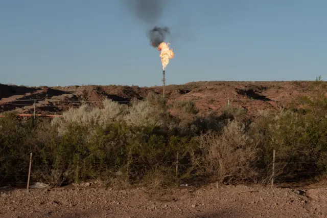 Una chimenea de escape de gas con la llama encendida en Vaca Muerta