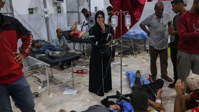 Una mujer mira con tristeza a los heridos de un ataque ocurrido dentro de un lugar de distribución de comida.