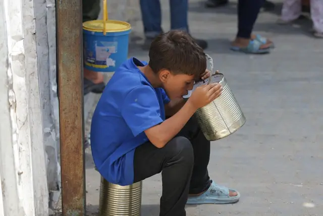 Un niño bebe de una lata en Gaza.
