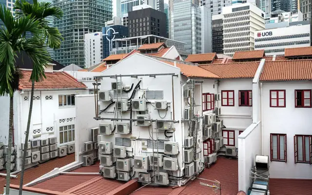Un conjunto de edificaciones en Singapur con múltiples equipos de aire acondicionado sobre sus paredes exteriores.