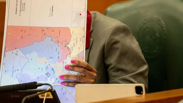 Una persona, con el rostro oculto, mira un documento en cuyo reverso hay un mapa que muestra un plan para la redistribución de los distritos de Texas.
