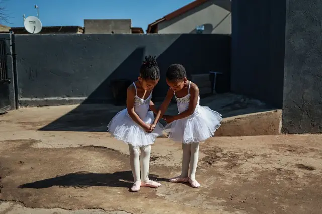 Las jóvenes estudiantes de ballet Philasande Ngcobo (izq.), de 5 años, y Yamihle Gwababa (der.), de 5 años, posan para una fotografía afuera de la Academia de Danza Mballet en Tembisa el 26 de julio de 2025.