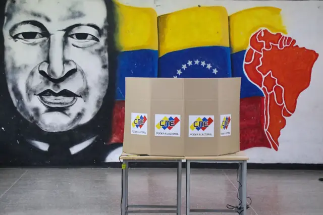 Una mesa de votación y detrás un mural de Chávez