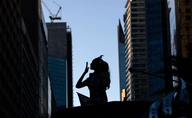 Mujer con corona lanza un beso a la multitud